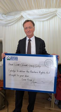 MP Andrew George holding a postcard reading "Dear West Cornwall + Isles  of Scilly, I pledge to deliver the Renters' Rights Act straight to your door. Love from Andrew"