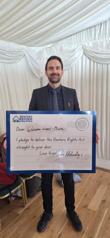 MP Dan Aldridge holding a postcard reading "Dear Weston-super-Mare, I pledge to deliver the Renters' Rights Act straight to your door. Love from Dan Aldridge" 
