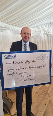 MP Joe Powell holding a postcard reading "Dear Kensington + Bayswater, I pledge to deliver the Renters' Rights Act straight to your door. Love from Joe Powell"